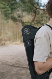 Uma pessoa transporta o tapete de ioga Earthle no saco às costas, na floresta